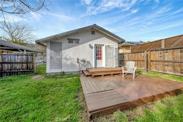 rear view of house featuring a yard, fence, a wooden deck, and stucco siding