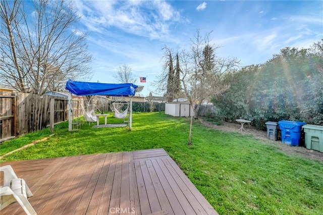 wooden deck featuring a shed, a lawn, an outdoor structure, and a fenced backyard