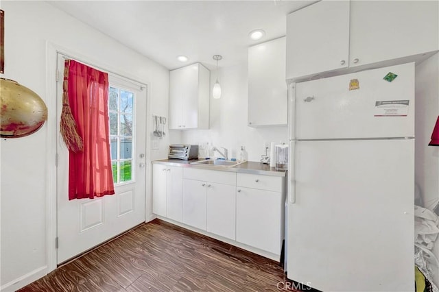 kitchen featuring dark wood-type flooring, freestanding refrigerator, white cabinetry, a sink, and recessed lighting