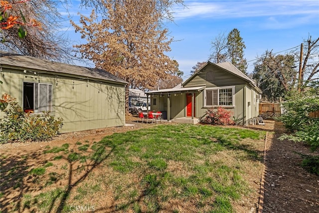 rear view of house featuring fence and a yard