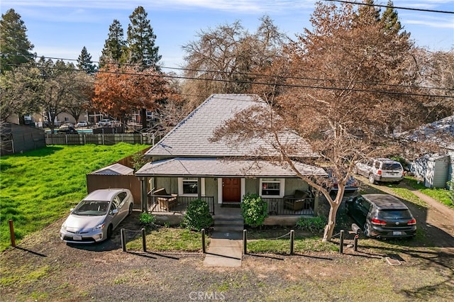 view of front of property with a shingled roof, fence, a porch, and a front lawn