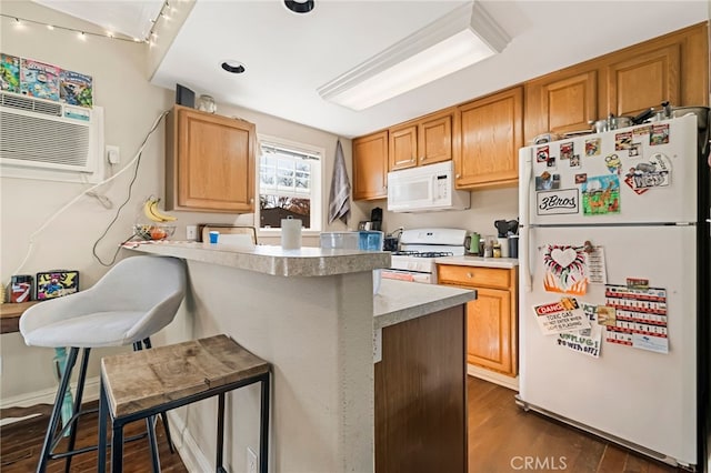 kitchen featuring a peninsula, white appliances, dark wood-style flooring, a breakfast bar, and a wall mounted air conditioner