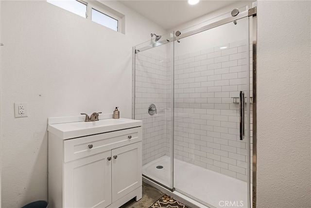 full bathroom featuring a textured wall, a shower stall, and vanity