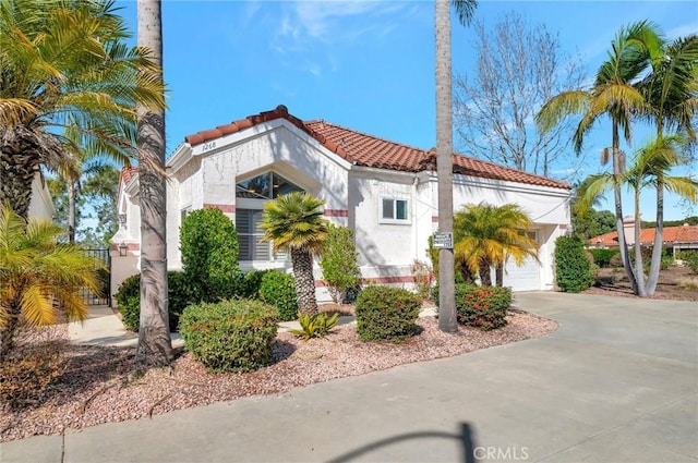 view of front of home with a tile roof, driveway, an attached garage, and stucco siding