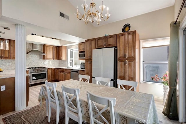 kitchen featuring appliances with stainless steel finishes, brown cabinetry, visible vents, and wall chimney range hood