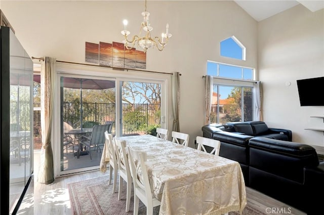 dining space featuring light wood-style floors, a notable chandelier, and a high ceiling