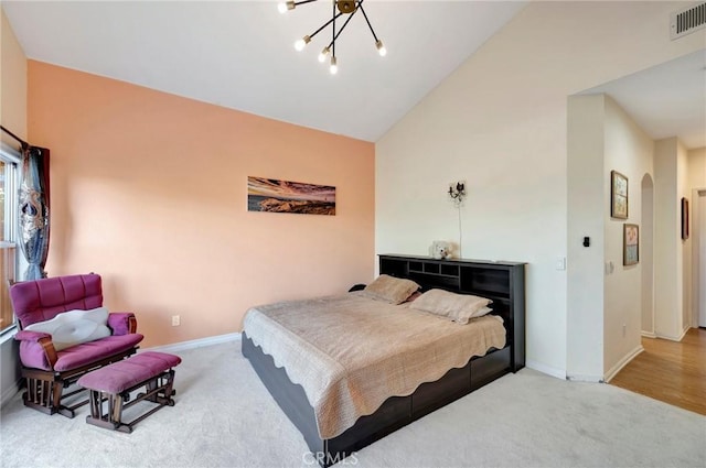 carpeted bedroom with arched walkways, visible vents, lofted ceiling, and baseboards