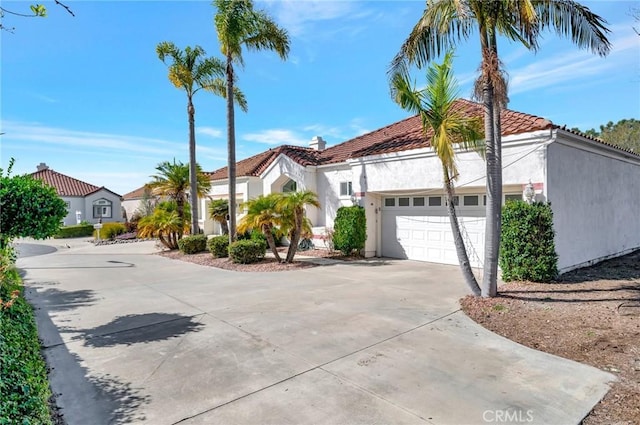 mediterranean / spanish-style home with an attached garage, a tile roof, concrete driveway, and stucco siding