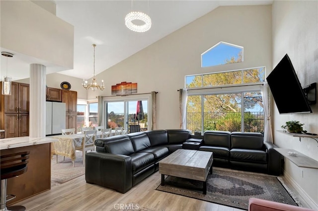 living area with high vaulted ceiling, a notable chandelier, and light wood finished floors