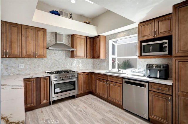 1268 Via, San Jacinto, San Marcos, CA 92078 - kitchen featuring wall chimney range hood, appliances with stainless steel finishes, light stone counters, light wood-style flooring, and decorative backsplash