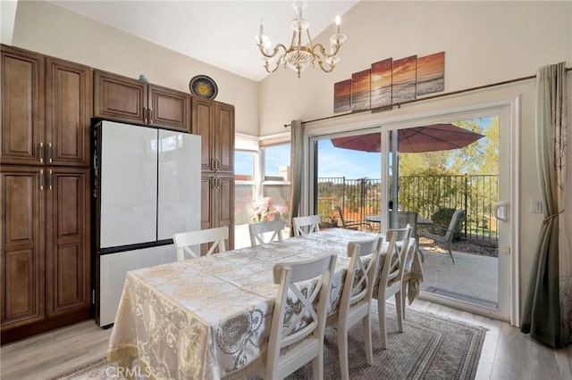 dining space with a chandelier, vaulted ceiling, and light wood-style floors