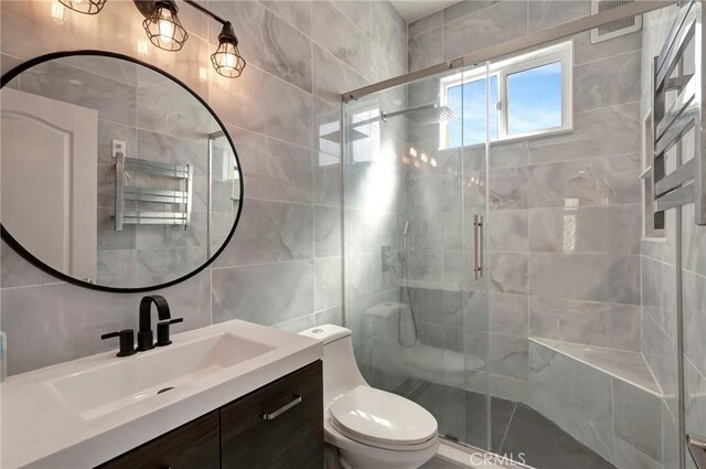 full bathroom featuring a stall shower, tile walls, vanity, and toilet