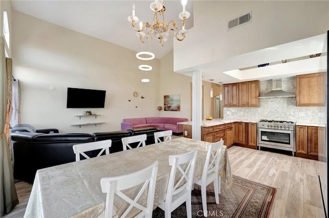 dining room featuring light wood finished floors, visible vents, high vaulted ceiling, and an inviting chandelier