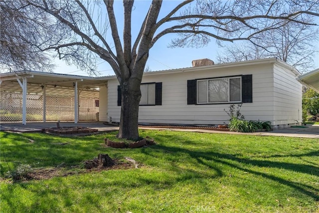 exterior space with a carport, a chimney, and a front lawn