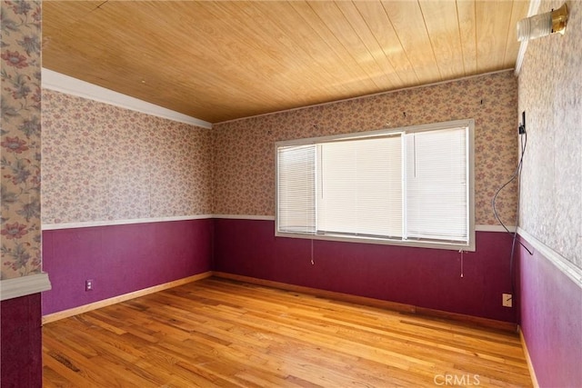 spare room featuring wallpapered walls, wood ceiling, a wainscoted wall, and wood finished floors