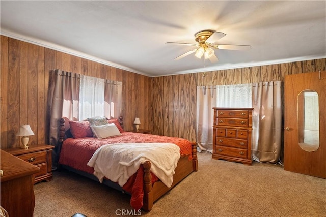 bedroom with ceiling fan, ornamental molding, carpet, and wooden walls