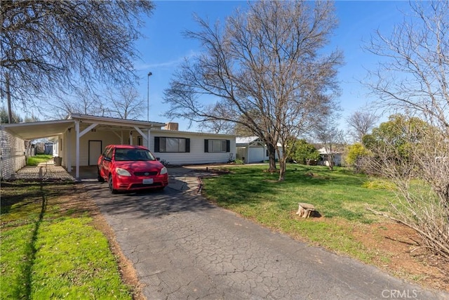 ranch-style house with a carport, a front lawn, and aphalt driveway