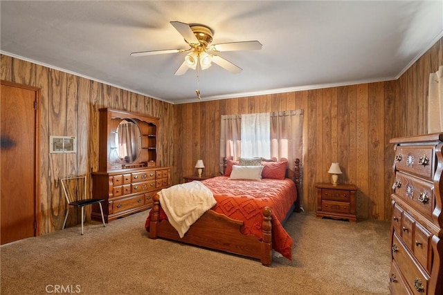 carpeted bedroom with ornamental molding, wooden walls, and a ceiling fan