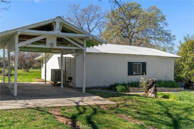 exterior space featuring metal roof, central AC, and a yard