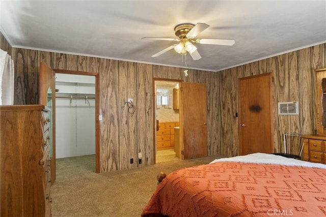 carpeted bedroom with connected bathroom, a ceiling fan, a closet, a walk in closet, and crown molding