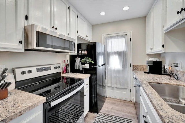 kitchen with recessed lighting, stainless steel appliances, a sink, white cabinets, and light wood finished floors