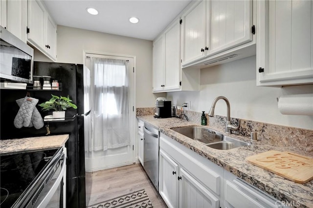 kitchen with light stone counters, a sink, white cabinets, appliances with stainless steel finishes, and light wood-type flooring