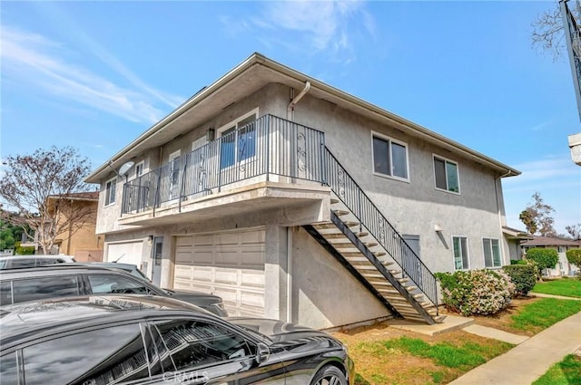 view of front of house featuring an attached garage, stairway, and stucco siding