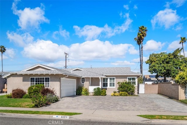 single story home featuring decorative driveway, fence, an attached garage, and stucco siding