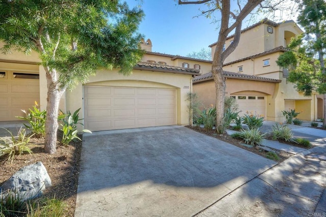 mediterranean / spanish-style home with a garage, a tiled roof, concrete driveway, and stucco siding