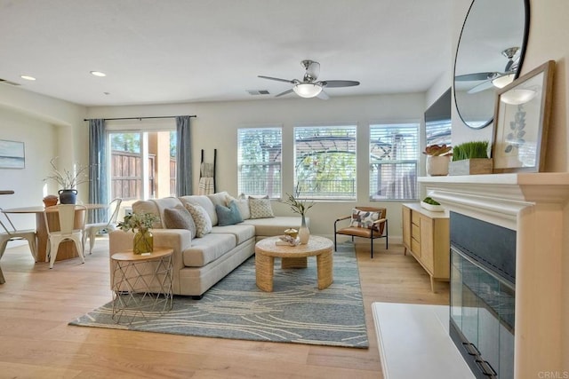 living room with recessed lighting, visible vents, a ceiling fan, a glass covered fireplace, and light wood-type flooring