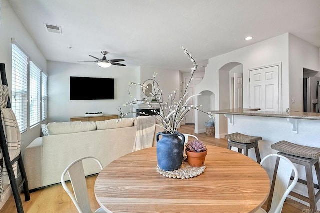 dining space featuring visible vents, arched walkways, a ceiling fan, light wood-style floors, and recessed lighting