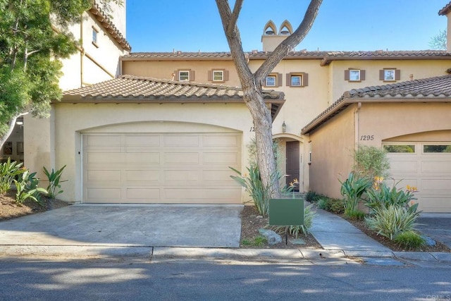 mediterranean / spanish-style house featuring driveway, an attached garage, a tiled roof, and stucco siding