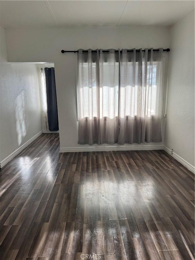 unfurnished room with dark wood-style floors and baseboards