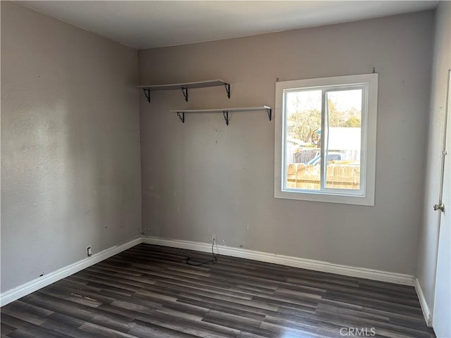 spare room with dark wood-type flooring and baseboards