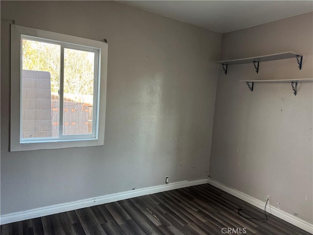 unfurnished room with dark wood-style floors and baseboards