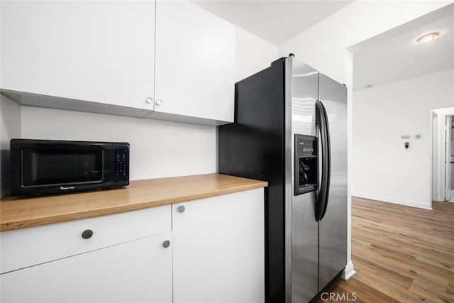 kitchen with stainless steel fridge, baseboards, white cabinets, wood finished floors, and black microwave