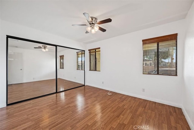 unfurnished bedroom featuring ceiling fan, a closet, baseboards, and wood finished floors