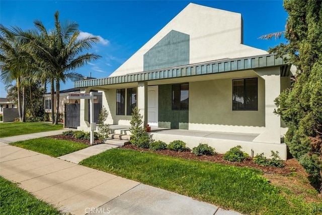 view of front of property featuring a porch, a front yard, and stucco siding