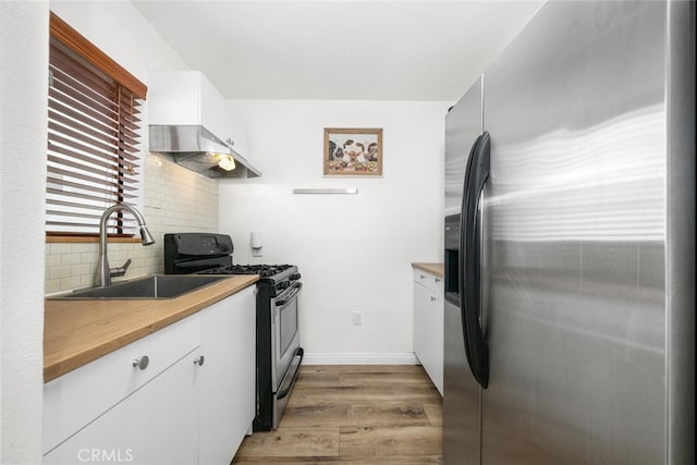 kitchen featuring under cabinet range hood, stainless steel appliances, a sink, white cabinets, and light wood finished floors