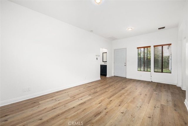 unfurnished room with hardwood / wood-style floors, visible vents, and baseboards