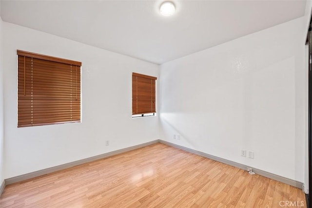 unfurnished room with light wood-type flooring and baseboards