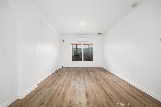 unfurnished room featuring wood finished floors, baseboards, and a wall mounted AC