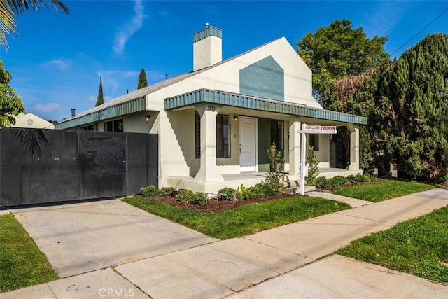 view of front of home with a gate, a porch, and stucco siding