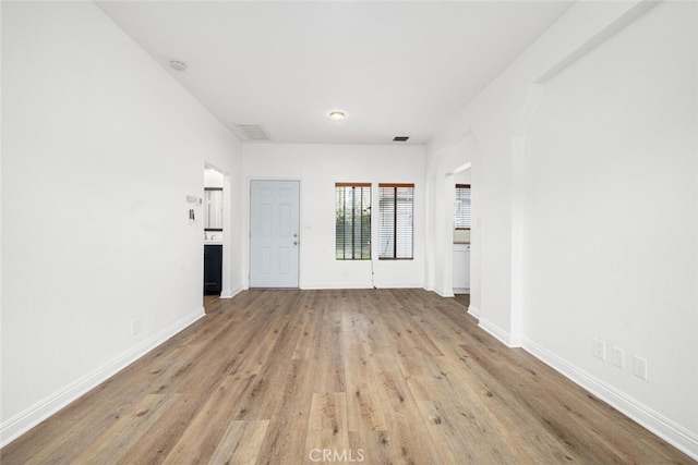 unfurnished room with light wood-style floors, visible vents, and baseboards