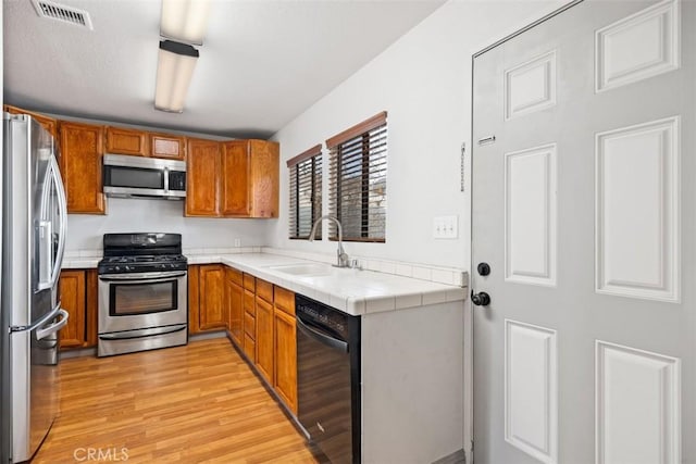 kitchen with brown cabinets, visible vents, stainless steel appliances, and a sink