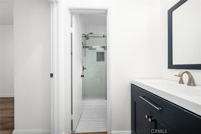 full bath featuring a shower stall, vanity, and baseboards