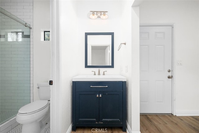 bathroom with toilet, a stall shower, wood finished floors, and vanity