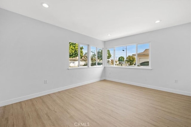 spare room with light wood-style floors, recessed lighting, a healthy amount of sunlight, and baseboards