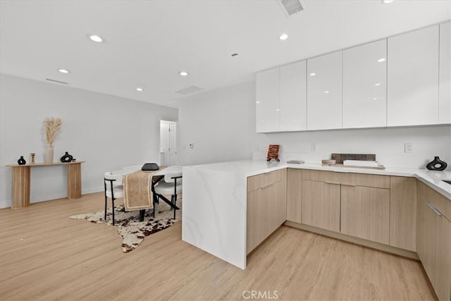 kitchen with light wood-style floors, light countertops, a peninsula, and modern cabinets