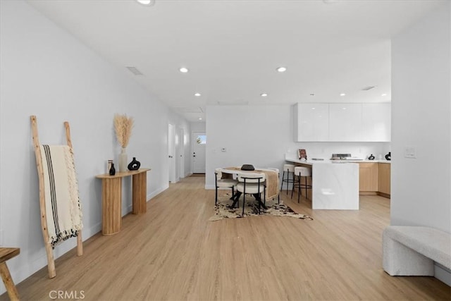 interior space with light wood finished floors, white cabinets, modern cabinets, light countertops, and recessed lighting